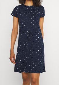 Robe bleu marine en coton doux, dotée d'un col rond, de manches courtes, de pois blancs et d'un détail de taille à cordon.