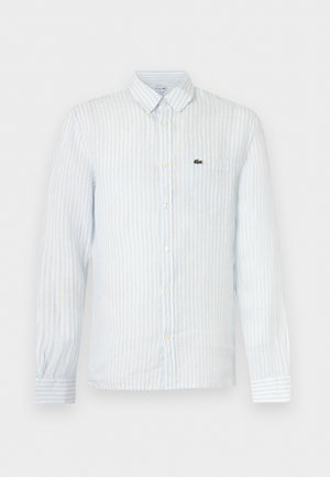 Πουκάμισο μακρυμάνικο με κουμπιά, ανοιχτό μπλε κατακόρυφες ρίγες, τσέπη μπροστά και μικρό πράσινο λογότυπο στο αριστερό στήθος.