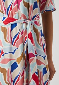 Šaty s květinovým vzorem, vyrobené z měkké a lehké látky v kombinaci modré, červené, růžové a hnědé barvy, s mašlí v pase.