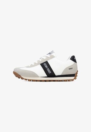 Zapatillas deportivas con cuero blanco y ante gris, franja negra, marca prominente y suela exterior de goma texturizada. Diseño de perfil bajo con cierre de cordones.