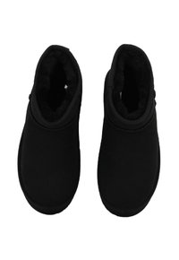 Pantofole nere, comode e slip-on, con un morbido rivestimento interno in peluche, progettate per calore e comfort, mostrate in vista dall'alto.