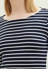 Gestreiftes Oberteil in Marineblau und Weiß mit einem Bootsausschnitt, aus weichem Stoff gefertigt, mit horizontalen Streifen und einer glatten Textur.