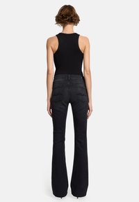 Schwarze Schlagjeans mit hoher Taille, zwei Gesäßtaschen und gestickten Details. Verfügt über eine glatte Denim-Oberfläche und eine taillierte Passform.