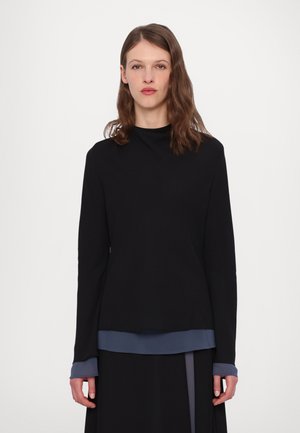 Sort langærmet bluse med høj hals og ensfarvet design. Den nederste kant har en kontrastfarvet blå accent, glat tekstur og en afslappet pasform.