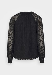 Blouse noire à manches longues en tissu transparent texturé avec un motif complexe en forme de vagues. Comprend un col froncé et des poignets boutonnés.