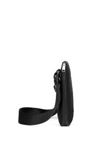 Borsa a tracolla nera realizzata in materiale tessurizzato, dotata di chiusura con zip e tracolla regolabile, con un profilo sottile e un design minimalista.