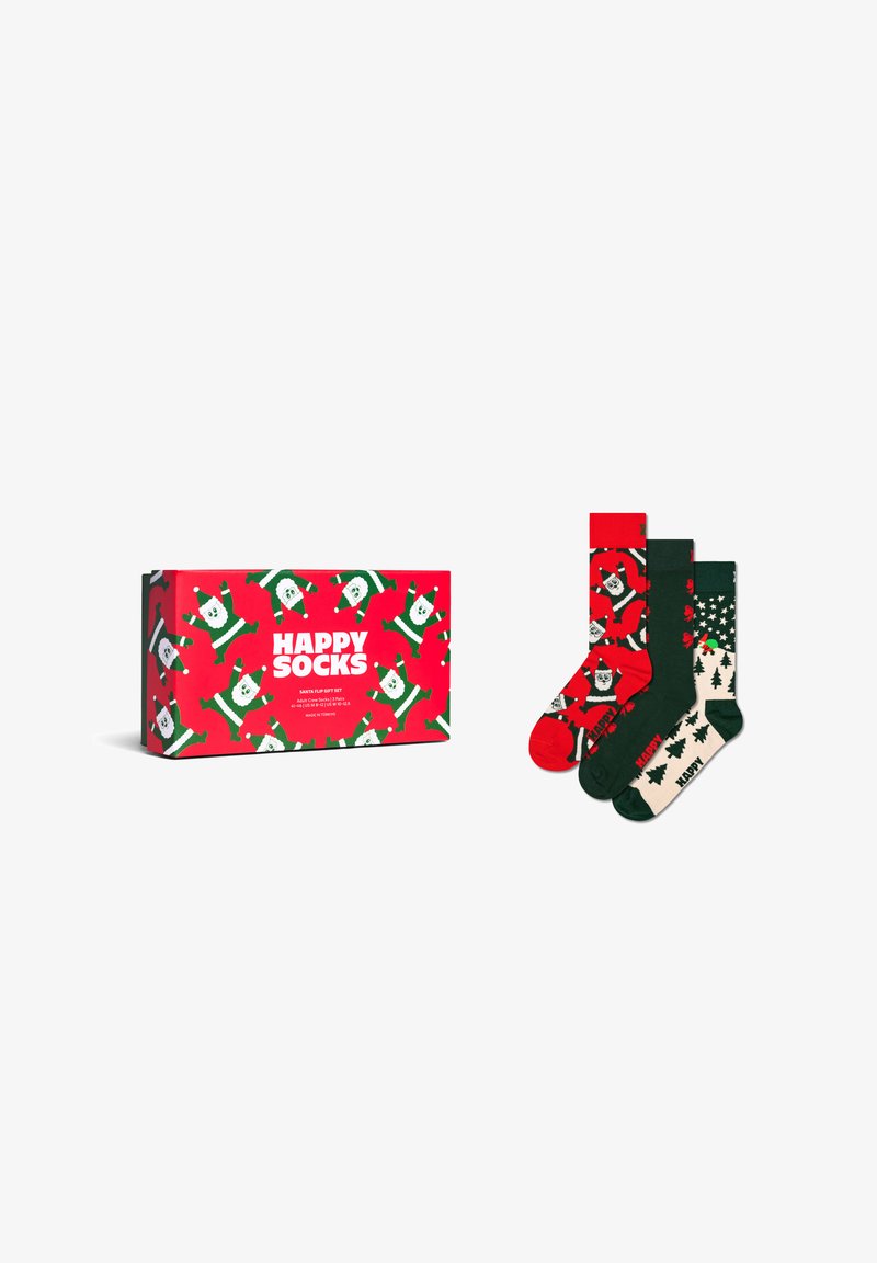 Zestaw trzech skarpet bożonarodzeniowych z wzorem Świętego Mikołaja i choinek obok dopasowanej czerwonej pudełka z napisem "Happy Socks".