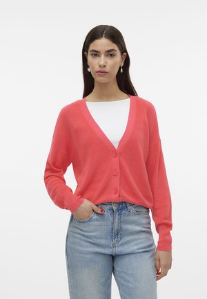 Koraalroze gebreide cardigan met lange mouwen en een V-hals, met drie knopen aan de voorkant en geribbelde accenten. Gecombineerd met hoge taille jeans.
