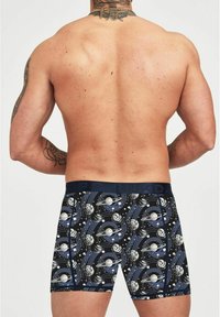 Boxer brev con tessuto blu scuro e stampa a tema spaziale, inclusi pianeti e vortici, con una fascia morbida in vita e una vestibilità aderente.