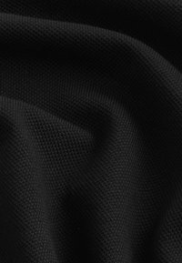 Svart texturerat tyg med ett subtilt geometriskt mönster, som har en mjuk, vävd yta och draperade veck som skapar djup och dimension.
