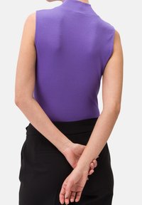 Top senza maniche di colore viola con colletto alto, caratterizzato da un design aderente. La vista posteriore rivela una texture liscia e uno stile minimalista.