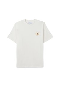 Camiseta de algodón blanca con mangas cortas, que presenta un pequeño emblema de un oso en dorado y marrón dentro de un diseño de laurel en el lado izquierdo del pecho.