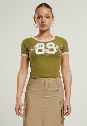 Olive green short-sleeve crop top with pink accents and white graphic print featuring "KARL KANI" and "BROOKLYN." Smooth fabric, fitted design.