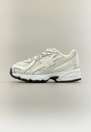 Weißer und beiger New Balance Sneaker mit Mesh-Einsätzen, reflektierenden Details und schwarzer Gummisohle, von der Außenseite gezeigt.