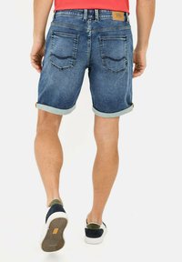 Herren Denim-Shorts in Mittelblau mit umgeschlagenen Säumen, ausgestattet mit einem Lederpatch am hinteren Bund und zwei Gesäßtaschen.