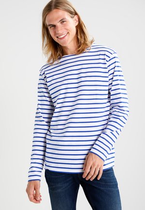 Langærmet stribet skjorte i hvid og blå, lavet af bomuld. Har brede vandrette striber og rund hals. Kombineret med mørk denim jeans.