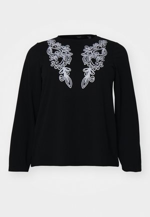 Crna majica dugih rukava s složenim srebrnim vezom oko izreza. Mekana tekstura, opušteni kroj i jednostavan dizajn s okruglim izrezom.