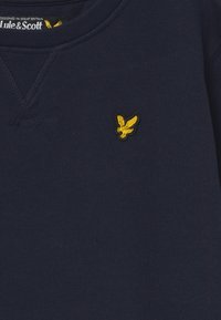 Granatowy sweatshirt z fakturowanej dzianiny, z małym żółtym haftowanym logo ptaka na piersi.