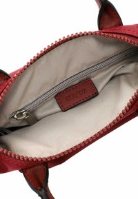 Red nylon bag interior with a smooth beige lining, a zippered pocket, and a textured red label. Accented with a red zipper.