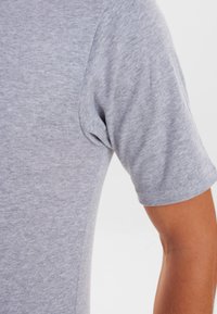 Kortærmet grå t-shirt lavet af blødt, struktureret stof, med en rund hals og en afslappet pasform, med synlige sømme langs ærmerne.
