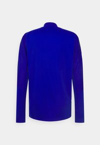 Langärmliges Oberteil aus tiefblauem Stoff mit figurnahem Schnitt und hohem Kragen. Glatte Textur mit minimalen Nähten.