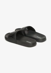 Sorte sandleder lavet af syntetisk materiale med brede stropper med præget branding. Glat tekstur og let design.
