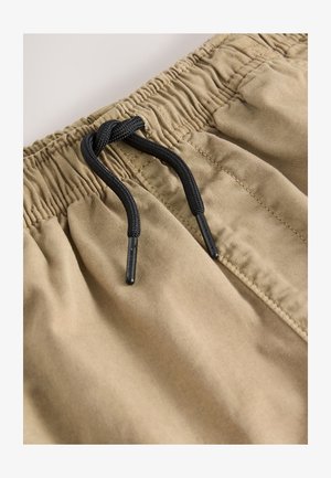 Smėlio spalvos medvilniniai šortai su elastinga juosmens juosta ir juodu raišteliu. Yra siuvimo detalės ir šoninės kišenės. Lygios tekstūros.