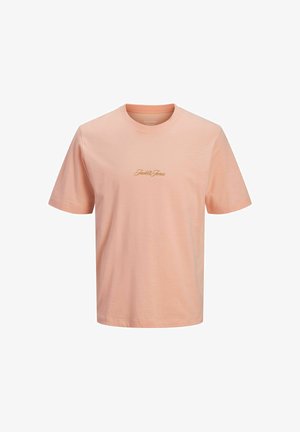 Jongen staand, draagt een lichtgroen overhemd met knopen over een roze T-shirt, spijkerbroekshorts, witte sokken en beige schoenen, tegen een effen witte achtergrond.