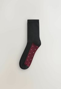Čierna ponožka s marhuľovou časťou ozdobenou bielymi bodkami. Hladký povrch, štandardná dĺžka a bez viditeľného brandingu.