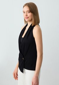 Top nero senza maniche con davanti drappeggiato e dettaglio annodato in vita, con un bottone d'accento dorato, realizzato in tessuto morbido.