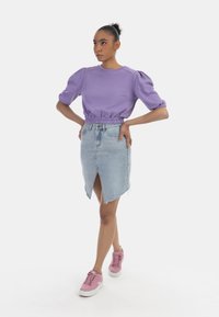 Lilla puffærmet top med en indsnøret talje, parret med en lys blå denimnederdel med en frontslid. Afsluttet med pink platform sko.