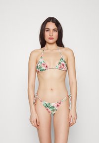 Conjunto de bikini com estampa floral, apresentando um top triangular e fundos ajustáveis com laço, feito de um tecido elástico em cores pastéis com um padrão de folhas.