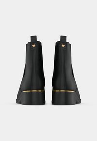 Svarte ankelstøvler laget av glatt skinn, med et gullaccent på hælen, og et hjerteemblem bak.