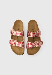 Roza sandala s srčnim potiskom, z dvema nastavljivima kovinskima zaponkama, pluto podplatom in gladkim zgornjim materialom.