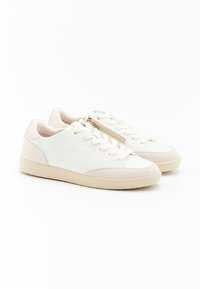 Sneaker bianchi con tomaia in pelle liscia, dettagli in suede, lacci piatti e una cerniera laterale. Presentano una suola in gomma beige.