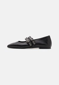 Chaussures plates en cuir noir avec un nez pointu, présentant deux brides décoratives avec des œillets en métal sur le coup de pied. Texture lisse et éclat subtil.