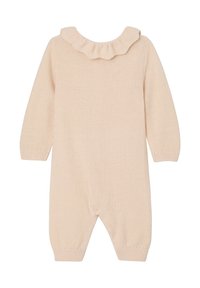 Strickoverall in sanftem Beige mit strukturiertem Finish und Rüschenausschnitt. Verfügt über lange Ärmel und enganliegende Bündchen an den Knöcheln.