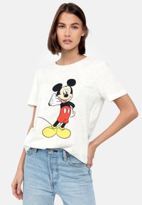 Hvid bomulds T-shirt med et farverigt Mickey Mouse grafik med sorte kanter, korte ærmer og en afslappet pasform, parret med lyseblå jeans.