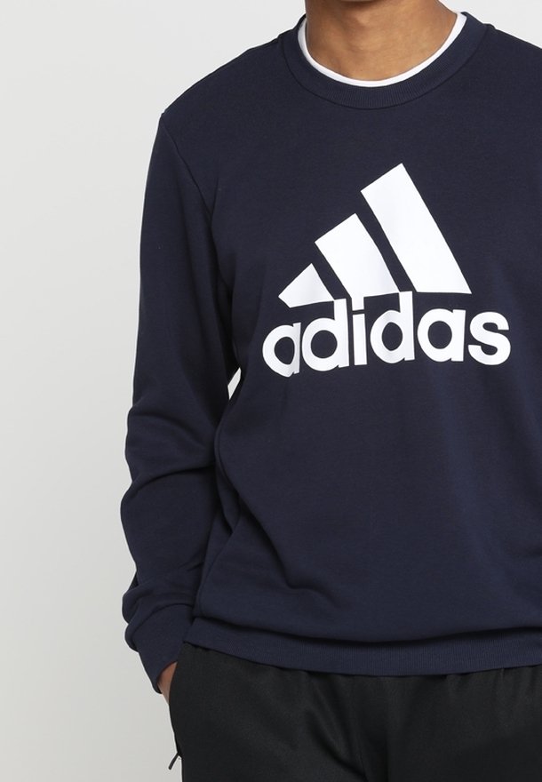 Sweatshirt bleu marine en mélange de coton avec manches longues, poignets côtelés et grand logo Adidas blanc sur la poitrine.