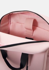 Różowa torba na zamek błyskawiczny z czarnymi elementami metalowymi. Wnętrze wyściełane gładką tkaniną i z paskiem do zabezpieczania przedmiotów. Minimalistyczny design z zaokrąglonymi uchwytami.