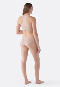 Lättvikts, sömlös beige sport-bh med breda axelremmar och matchande trosor. Mjuk textur och åtsittande design, lämplig för aktivt bruk.