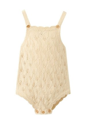 Combinaison pour bébé en maille crème avec motif feuillu, bretelles et boutons en bois aux bretelles et à l'entrejambe pour la fermeture.