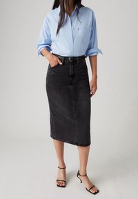 Ljusblå skjorta med knappar, svart denim midi kjol med fickor och svarta sandaler med remmar och klack. rena linjer, minimal hårdvarudetalj.