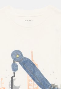 Lichtgekleurde katoenen t-shirt met een grafisch ontwerp van een blauwe robotarm, met een halve maan en een stadsaanzicht in pasteloranje en grijze accenten.