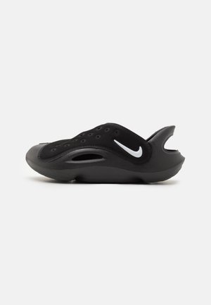 Sabot noir Nike à enfiler avec trous de ventilation et logo Swoosh blanc, avec talon ouvert et design respirant.