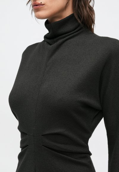 Sötétszürke, bordázott mintázatú garbó pulóver, testhezálló szabással, valamint finom csavart részlettel a deréknál az extra dizájnért.