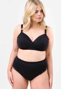 Svart bh och högmidjade trosor i mjukt tyg. Bh:n har vågig spetskant och justerbara axelremmar. Slät textur.