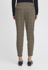 Pantalones con patrón a cuadros en negro y beige, con un ajuste slim y piernas entalladas, con una cinturilla elástica y bolsillos traseros.