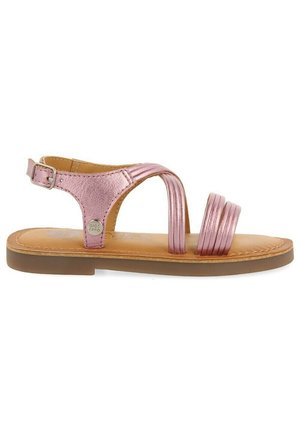 Sandal de metal rosa con suela plana, múltiples correas en el empeine y cierre de hebilla en el tobillo. Textura de cuero suave y diseño minimalista.