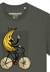 Dunkelgrünes T-Shirt mit einem cartoonhaften Bananencharakter, der Fahrrad fährt, mit gelben und schwarzen Designelementen und beigen Rädern.